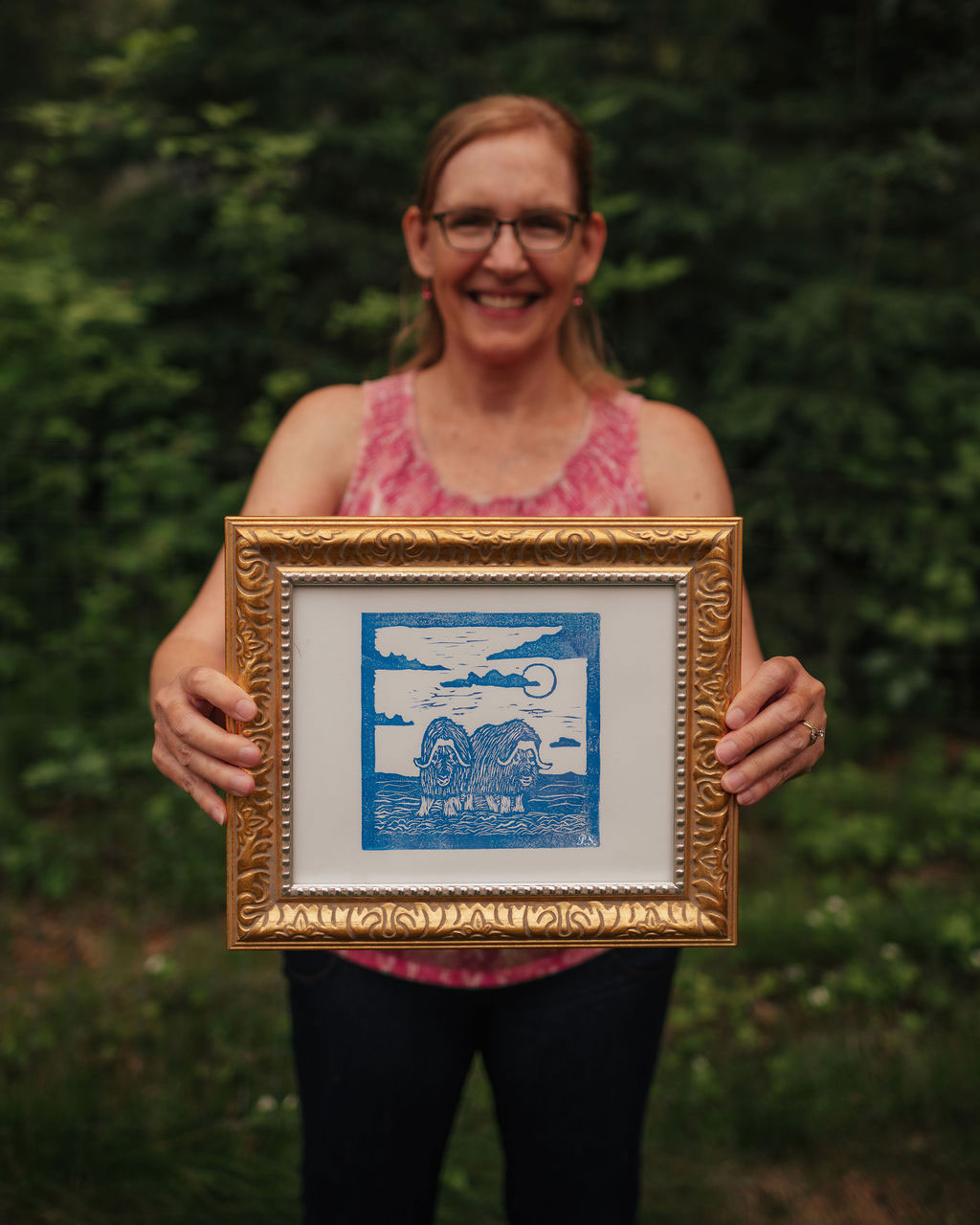 Alaskan artist, Pamela Sue, is holding a copy of her hand pressed Muskox print (royal blue). Prints are available in 3 colors at PamelaSueArtandDesigns.com